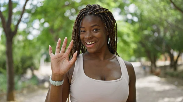 African american woman smiling confident saying hello with hand at park
