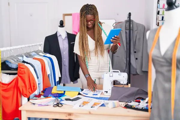 African american woman tailor using touchpad drawing clothing design at tailor shop