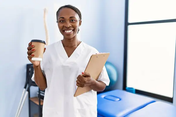 African American Woman Physiotherapist Holding Medical Report Drinking Coffee Rehab — Foto de Stock