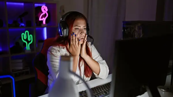 Overworked and stressed young redhead female streamer, battling stress while streaming a game from her gaming room late at night
