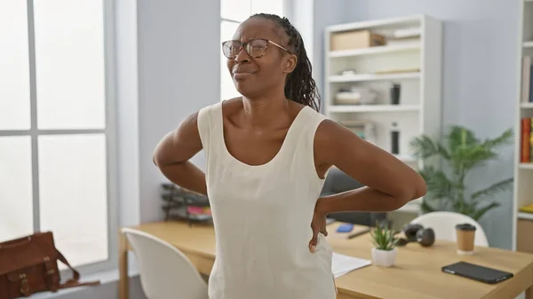 Young African American Woman Office Attire Experiences Back Pain While — Stock Photo, Image
