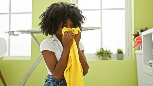 非洲裔美国妇女在洗衣房洗衣服时闻到干净毛衣的味道 — 图库照片