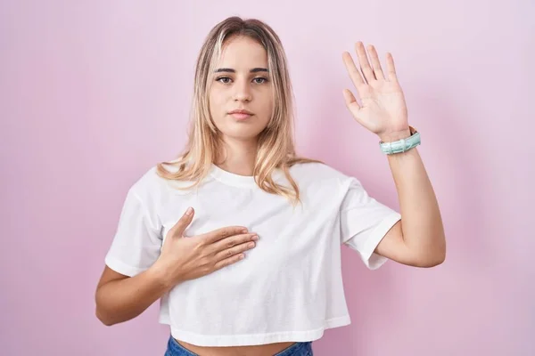 Jonge Blonde Vrouw Staan Roze Achtergrond Vloeken Met Hand Borst — Stockfoto