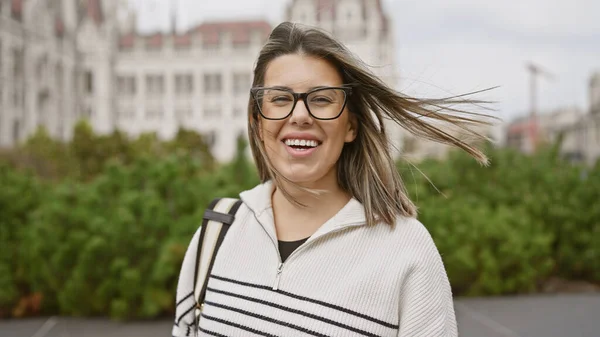 带着眼镜微笑的年轻惊慌失措的女人 背景在城市 背景是议会 — 图库照片
