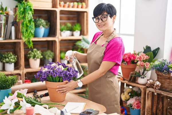 Middle age chinese woman florist using diffuser working at flower shop