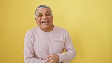 Kahkahalar içinde patlayan, orta yaşlı, neşeli, gri saçlı, süveter giyen, sarı arka planda tek başına duran, komik bir şakaya kahkahalarla gülen,.