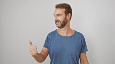 Neşeli orta yaşlı İspanyol adam izole edilmiş beyaz duvarın karşısında mutlu bir şekilde baş parmakları havada, ağzı açık bir şekilde gülümseyen pozitif duygu ve güveni gösteriyor..