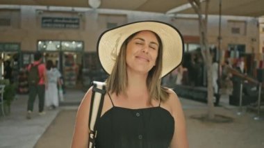 Güneş şapkası takan gülümseyen bir kadın Dubai 'de hareketli bir pazar yerinde güneşli bir günün tadını çıkarıyor..
