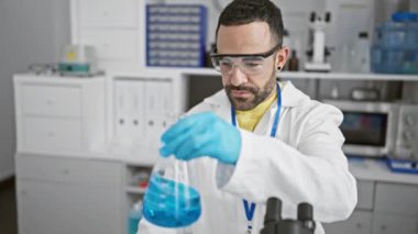 Latin bilim adamı labaratuarda mavi sıvıyı analiz ediyor.