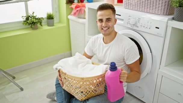 Schöner Mann Mit Waschmittel Und Einem Korb Einer Hellen Waschküche — Stockvideo