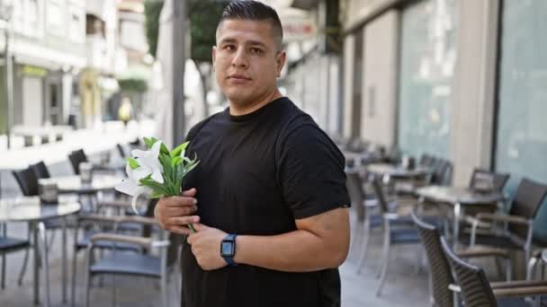 涼しい若いラテン語の男は晴れた街路に立って 彼の時計を見て 活気に満ちた春の花の花束を握る手 — ストック動画