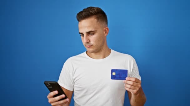 Usmívající Mladý Muž Držící Kreditní Kartu Při Použití Smartphonu Modrém — Stock video