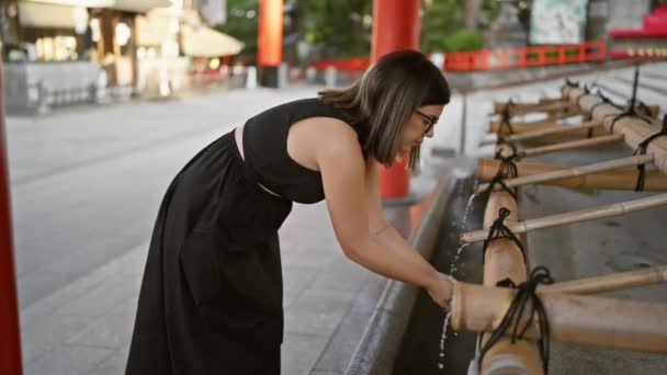 ガラスの美しいヒスパニック女性は 伝統的な浄化儀式を遂行し 竹林の中で京都の精神的な素晴らしさを手洗いする — ストック動画