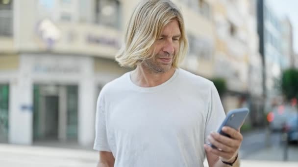Красивий Чоловік Довгим Світлим Волоссям Використовує Смартфон Святкує Міській Вулиці — стокове відео