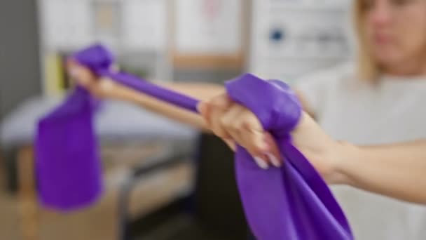 Сфокусированные Женские Упражнения Фиолетовыми Полосами Сопротивления Яркой Физиотерапевтической Клинике Указывающие — стоковое видео