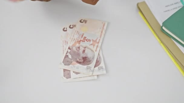 トルコのリラ紙幣のクローズアップ屋内ビューとオフィス用品付きの白い背景に対する人の手 — ストック動画