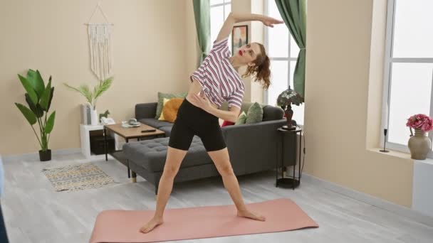 在一个装饰时尚的现代客厅里 一个健康的女人在粉色的垫子上做瑜伽伸展动作 — 图库视频影像