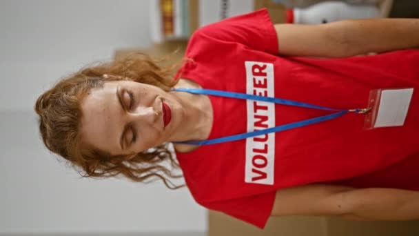 Cheerful Caucasian Woman Wearing Red Volunteer Shirt Badge Poses Indoors — Stock Video