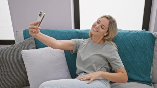 Eine Junge Blonde Frau Macht Ein Selfie Auf Ihrer Couch — Stockvideo