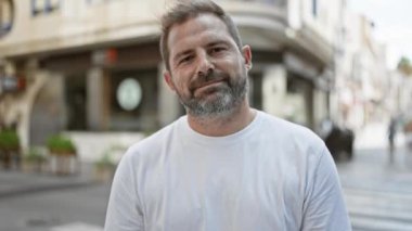 Gri saçlı, yakışıklı, olgun bir adam şehir sokaklarında başparmak kaldırıyor..