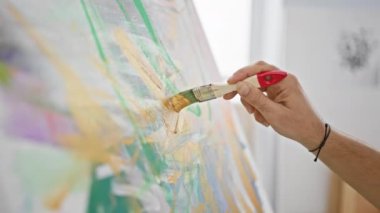 Bir sanatçının elinin, bir stüdyoda fırçayla tuvale yaptığı resim, yaratıcılığı ve zanaatkarlığı gösteriyor