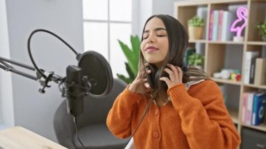 Bir radyo stüdyosunda mikrofon ve kulaklıkla müzik dinlemekten hoşlanan İspanyol bir kadın.