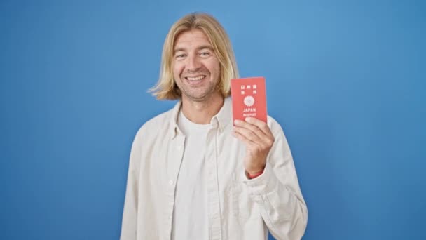 Sonriente Hombre Rubio Mostrando Pasaporte Japonés Sobre Fondo Azul Concepto — Vídeos de Stock