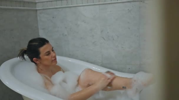 Μια Χαλαρή Γυναίκα Απολαμβάνει Ένα Αφρόλουτρο Μια Λευκή Μπανιέρα Μέσα — Αρχείο Βίντεο