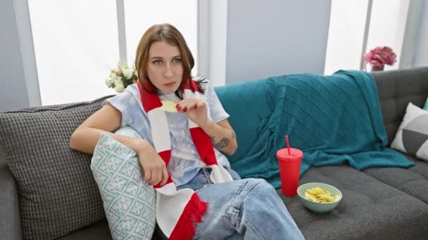 一位随意的年轻女子在舒适的室内沙发上享受着薯片 带着优雅的质朴气氛描绘着 — 图库视频影像