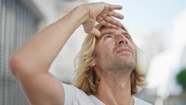 Blonder Mann Schirmt Augen Vor Sonne Auf Der Stadtstraße — Stockvideo