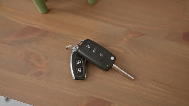 家のインテリアの設定で木製のテーブルの車のキーのために人の手が届きます — ストック動画