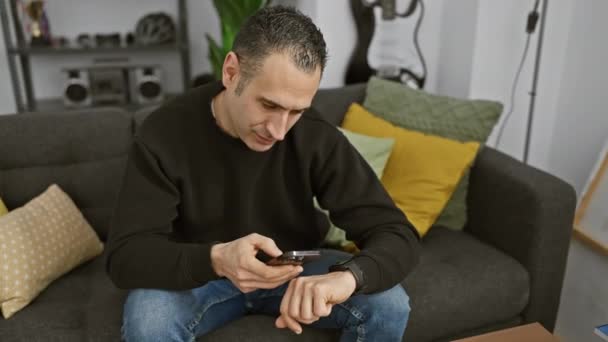 Орієнтований Чоловік Перевіряє Час Смарт Годиннику Тримаючи Телефон Затишній Вітальні — стокове відео