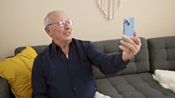 Evdeki Kanepede Oturan Neşeli Yaşlı Adam Akıllı Telefonuyla Kendini Ifade — Stok video