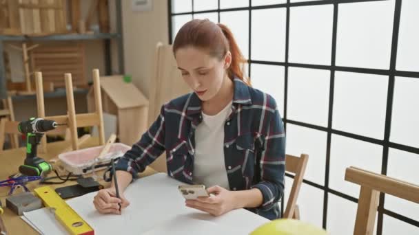Fokuseret Kvinde Ved Hjælp Smartphone Træværksted Omgivet Værktøjer Møbelprojekter – Stock-video