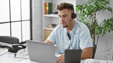 Modern ofis çalışma alanında bilgisayar ve tablet kullanan odaklanmış bir adam.