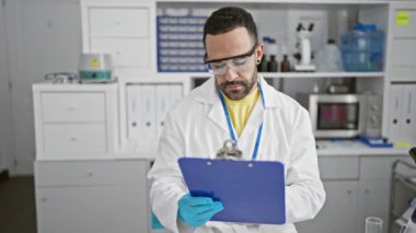 Laboratuvar önlüğü ve güvenlik gözlüğü takan İspanyol bilim adamı laboratuvar ortamında belgeleri inceliyor.