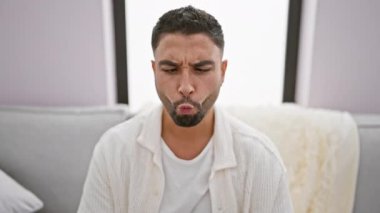 Arsız genç Arap adam oturma odasındaki kanepede oturuyor, komik bir balık suratı ve komik dudaklar yapıyor. Evdeki komik ifade!