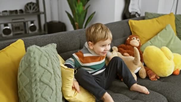 Playful Toddler Boy Smiles Cozy Couch Stuffed Toys Colorful Living — Stock Video