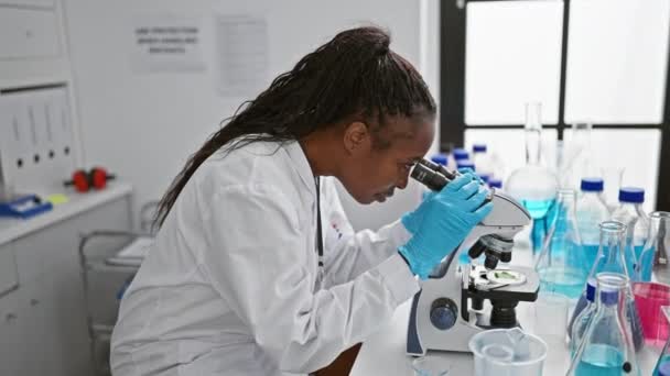 Cientista Afro Americana Usando Microscópio Laboratório Moderno Com Copos Frascos — Vídeo de Stock