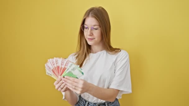 金发女人在一个黄色孤立的背景下审视挪威克朗 描绘金融和货币 — 图库视频影像