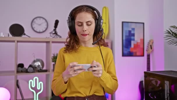 Neşeli Bir Kadın Renkli Bir Oyun Odasında Telefonuyla Oyun Oynuyor — Stok video