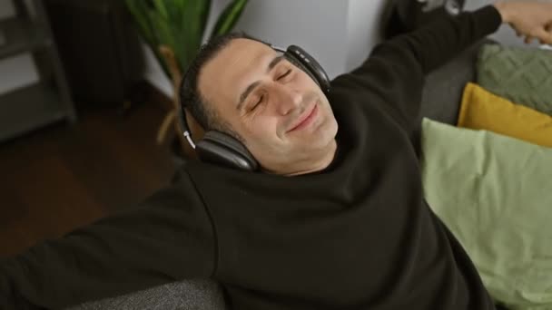 Evde Rahat Bir Adam Gözleri Kulaklıkları Kapalı Kanepe Yastıklarıyla Çevrili — Stok video