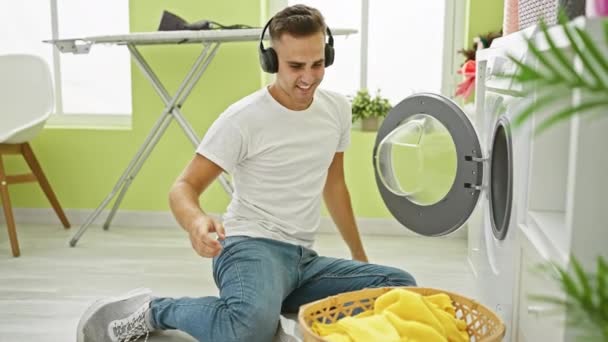 Młody Mężczyzna Dostosowuje Słuchawki Podczas Prania Jasnym Pomieszczeniu Przekazując Przyjemne — Wideo stockowe