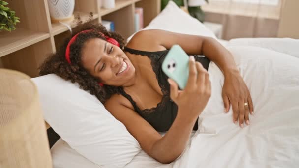 非洲裔美国女人在卧室里用智能手机微笑 — 图库视频影像