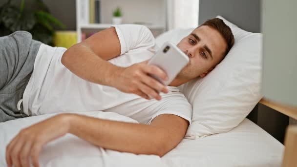 Young Hispanic Man Using Smartphone Bedroom Portraying Modern Indoor Lifestyle — Stock Video