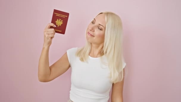 一个快乐的年轻女子 带着法国护照 脸上带着自信的表情和友好的微笑 在粉红的背景上摆出一副不错的标志 — 图库视频影像