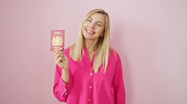 Neşeli genç sarışın kadın, pembe arka planda Kuzey İrlanda pasaportu dişlek bir gülümsemeyle kendine güveni yayıyor.