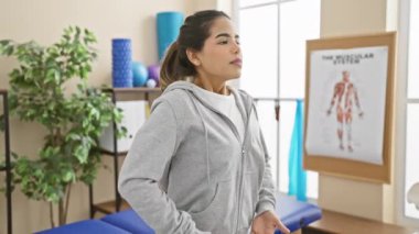 Genç bir İspanyol kadın bir rehabilitasyon kliniğinin parlak odasında nefes egzersizi yapıyor..