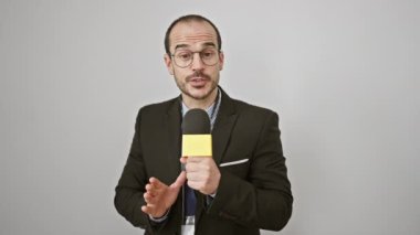 Gözlüklü, kendine güvenen bir adam mikrofona doğru konuşur..