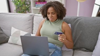 Afrikalı Amerikalı kadın evde kredi kartıyla online alışveriş yapıyor.